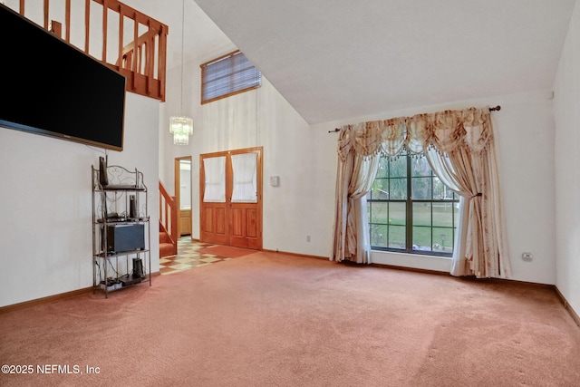 unfurnished living room with carpet floors and high vaulted ceiling