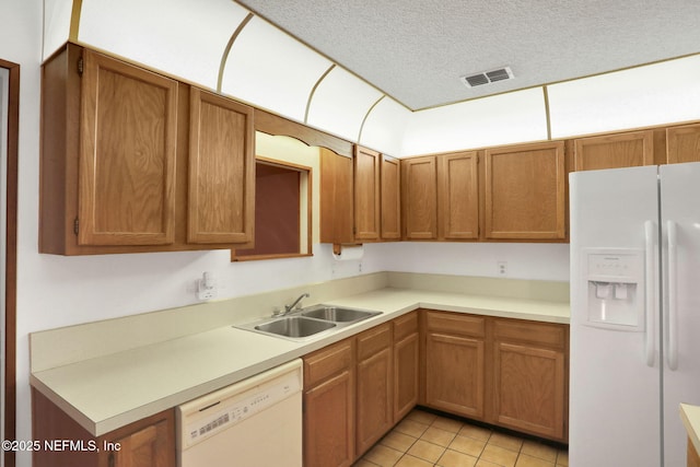 kitchen with light tile patterned flooring, sink, a textured ceiling, and white appliances