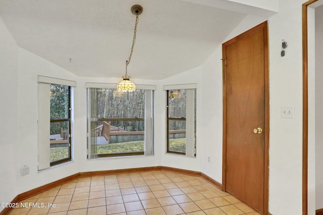 unfurnished dining area featuring vaulted ceiling and light tile patterned flooring