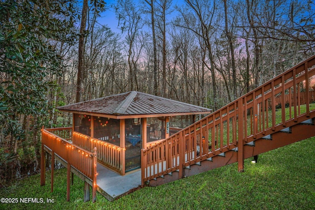 deck at dusk with a sunroom and a yard