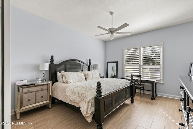 bedroom with ceiling fan, light hardwood / wood-style floors, and a textured ceiling