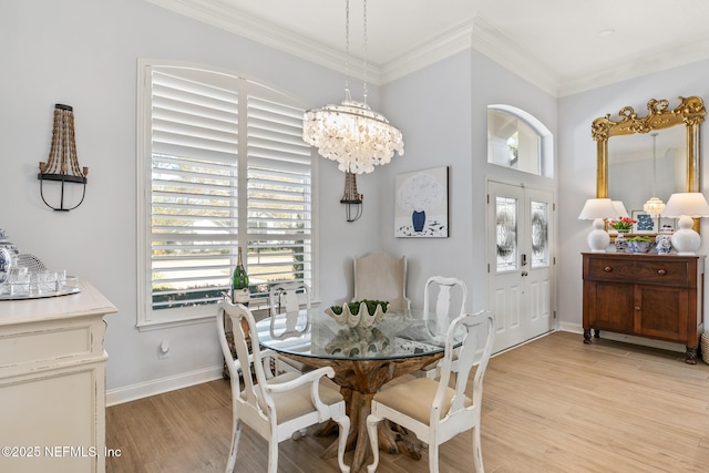 dining area featuring a notable chandelier, ornamental molding, and light wood-type flooring