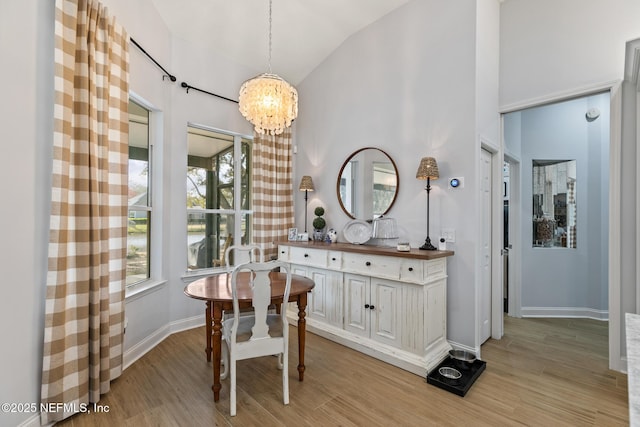 dining area featuring a high ceiling, a chandelier, and light wood-type flooring