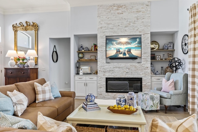 living room with crown molding, built in shelves, and a fireplace