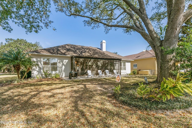 rear view of property with a hot tub, a patio area, and a lawn