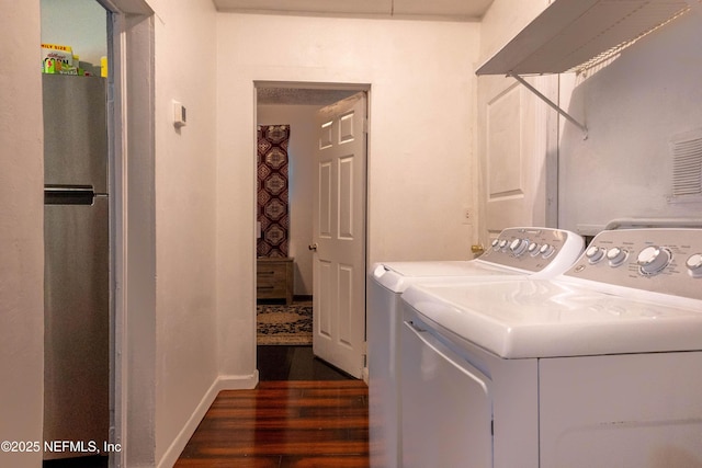 clothes washing area with dark hardwood / wood-style flooring and independent washer and dryer