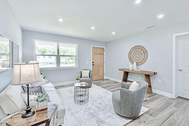 living room with a textured ceiling and light hardwood / wood-style flooring