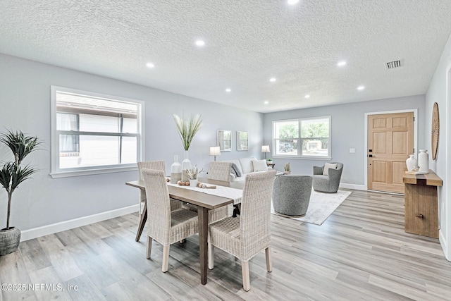 dining area featuring a textured ceiling and light hardwood / wood-style flooring