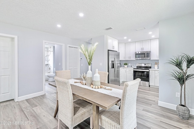 dining room with a textured ceiling and light hardwood / wood-style flooring