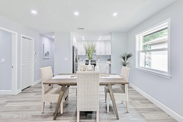 dining space featuring a textured ceiling and light wood-type flooring