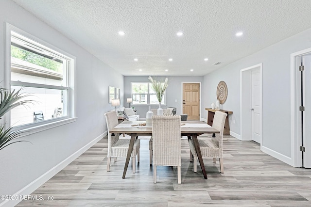 dining room with a textured ceiling and light hardwood / wood-style flooring