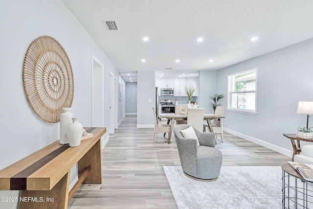 living room with a textured ceiling and light wood-type flooring