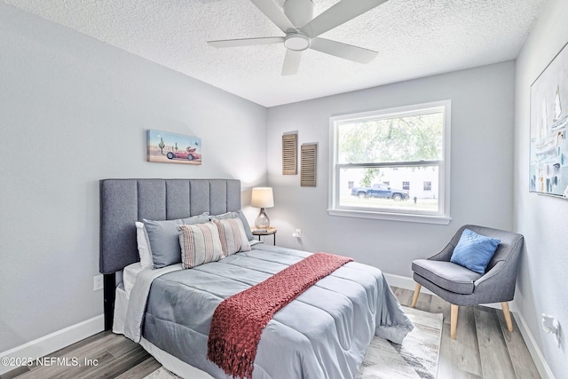 bedroom with ceiling fan, hardwood / wood-style floors, and a textured ceiling