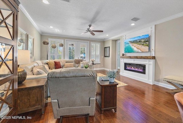 living room featuring dark wood-type flooring, a textured ceiling, and ornamental molding