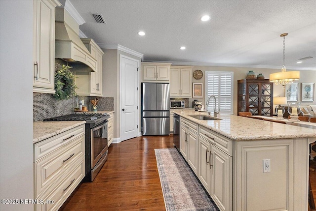 kitchen featuring decorative light fixtures, custom exhaust hood, sink, a kitchen island with sink, and stainless steel appliances