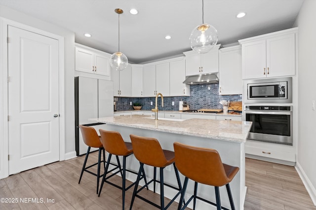 kitchen featuring stainless steel appliances, white cabinetry, and a kitchen island with sink