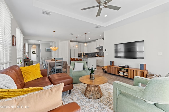 living room featuring ceiling fan, sink, and light hardwood / wood-style floors