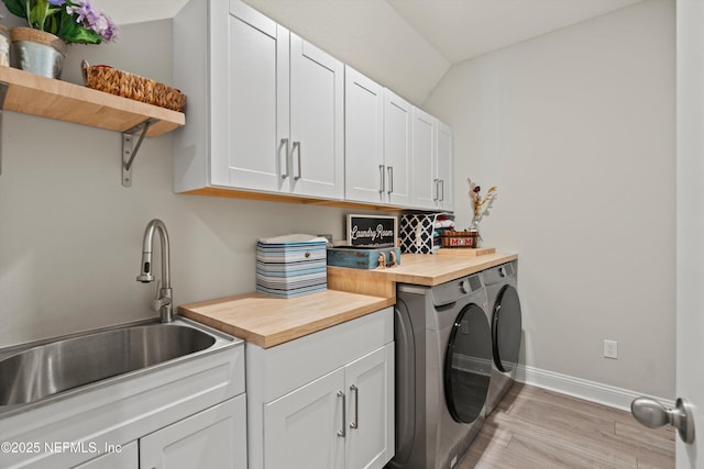 laundry room with sink, light hardwood / wood-style floors, cabinets, and washing machine and clothes dryer