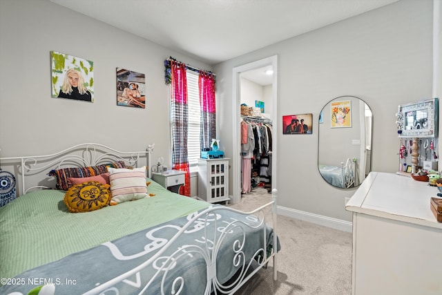 bedroom with a walk in closet, light carpet, and a closet