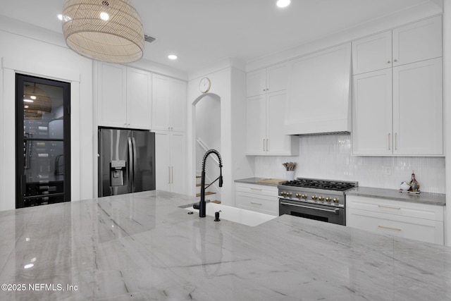 kitchen featuring backsplash, sink, light stone countertops, stainless steel appliances, and white cabinets