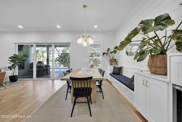 dining area with wine cooler, a notable chandelier, and light hardwood / wood-style flooring