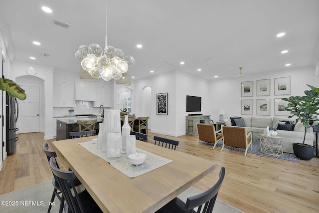 dining space featuring a chandelier, light wood-type flooring, and ornamental molding