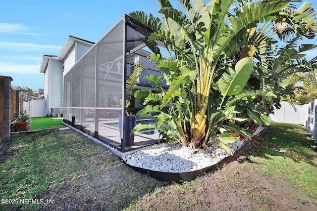 view of side of home featuring a lanai and a lawn