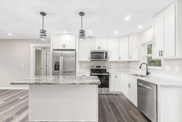 kitchen with appliances with stainless steel finishes, sink, white cabinetry, and a kitchen island