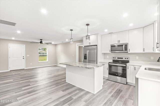 kitchen featuring white cabinetry, a center island, stainless steel appliances, and hanging light fixtures