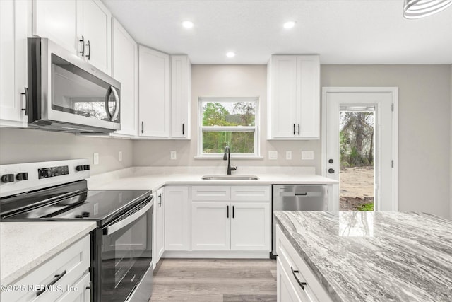 kitchen with light stone counters, sink, white cabinets, and stainless steel appliances