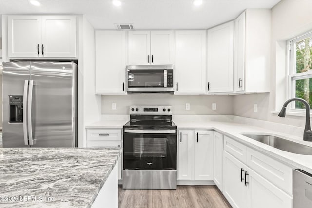 kitchen with appliances with stainless steel finishes, white cabinetry, and sink