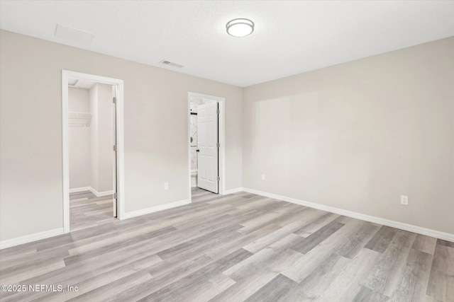 unfurnished room featuring a textured ceiling and light hardwood / wood-style flooring