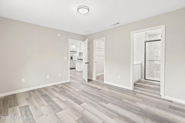 unfurnished room featuring a textured ceiling and light hardwood / wood-style flooring