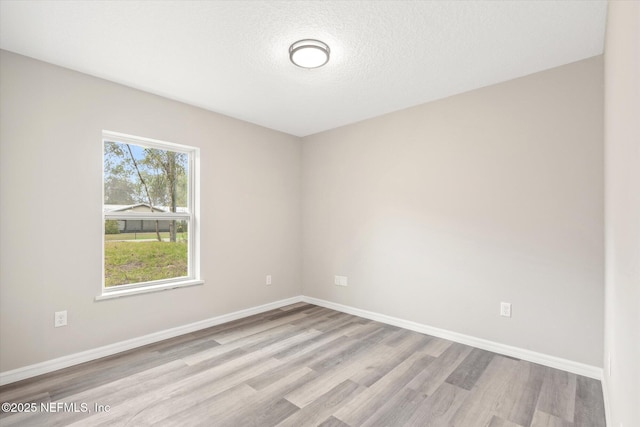 unfurnished room with a textured ceiling and light hardwood / wood-style flooring