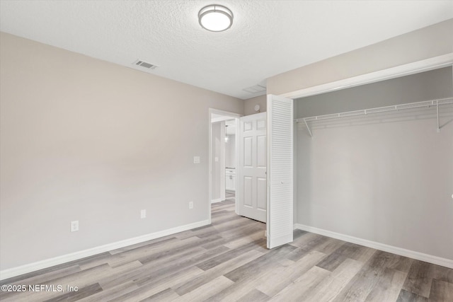 unfurnished bedroom featuring a textured ceiling, a closet, and light wood-type flooring