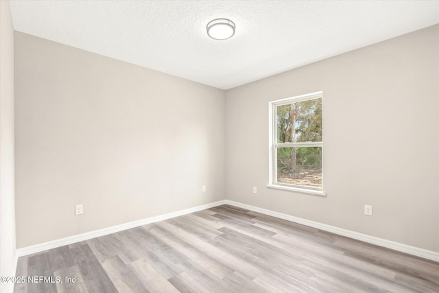 unfurnished room with a textured ceiling and light hardwood / wood-style flooring