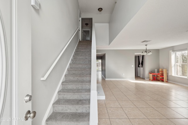 staircase featuring tile patterned floors and a notable chandelier