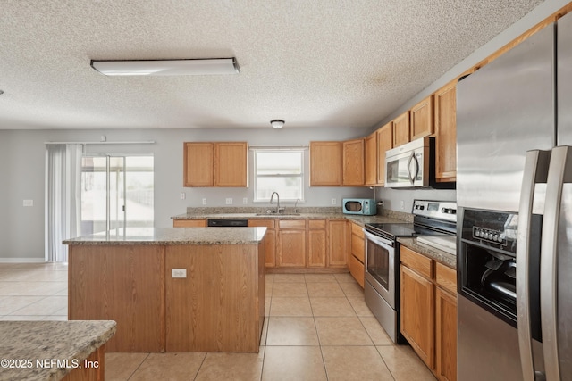 kitchen featuring a center island, light tile patterned floors, sink, stainless steel appliances, and a healthy amount of sunlight