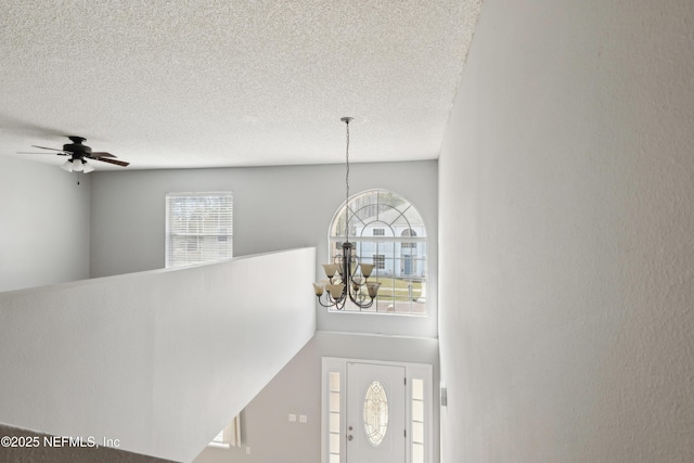 foyer with a textured ceiling, a notable chandelier, and a wealth of natural light