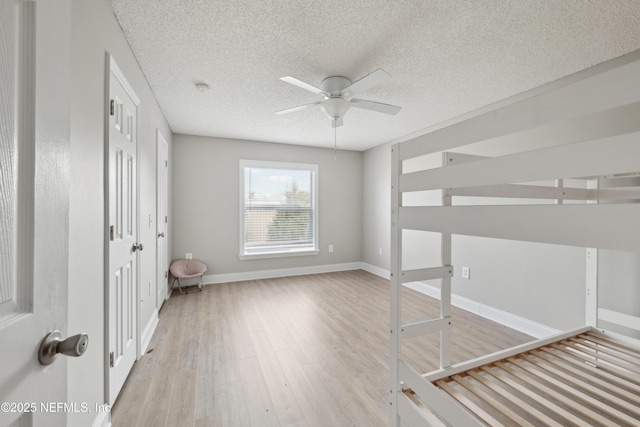 unfurnished bedroom with ceiling fan, light hardwood / wood-style floors, and a textured ceiling