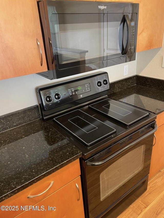 kitchen featuring dark stone counters and black appliances