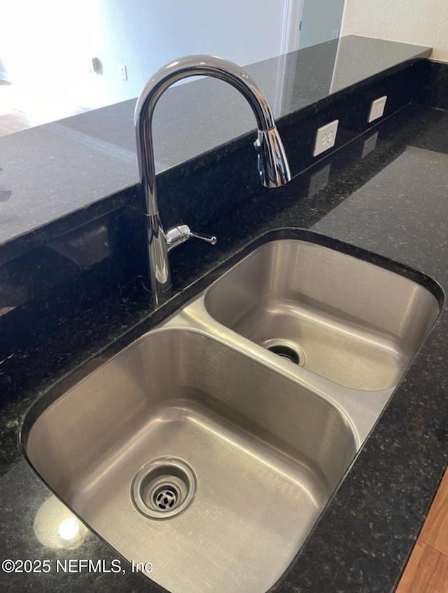 details with sink, hardwood / wood-style floors, and dark stone counters