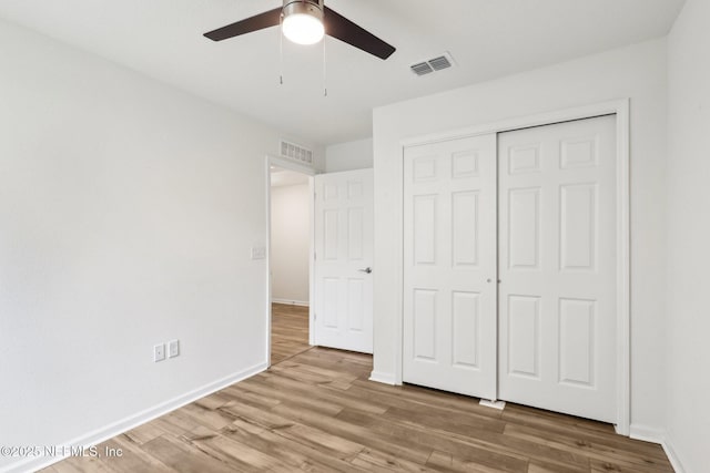 unfurnished bedroom featuring hardwood / wood-style floors, a closet, and ceiling fan