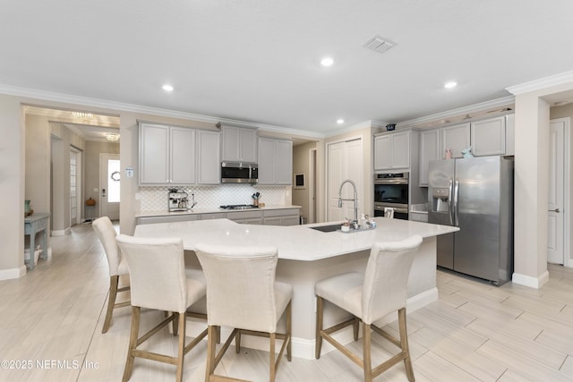 kitchen with a kitchen island with sink, sink, gray cabinetry, and stainless steel appliances