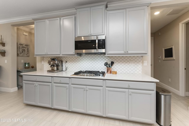 kitchen featuring decorative backsplash, ornamental molding, stainless steel appliances, and gray cabinetry