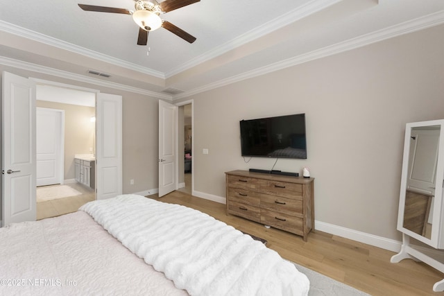 bedroom with a tray ceiling, light hardwood / wood-style floors, ceiling fan, ensuite bathroom, and crown molding