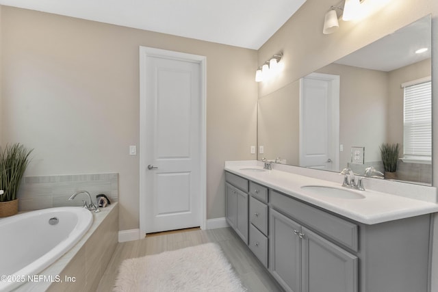 bathroom featuring tiled tub and vanity