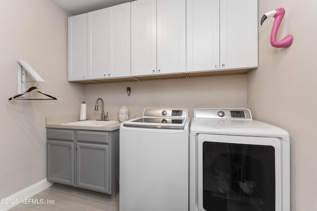 laundry area featuring light tile patterned floors, washing machine and dryer, sink, and cabinets