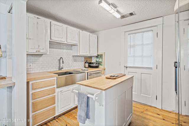 kitchen with light hardwood / wood-style floors, sink, white cabinetry, and wood counters