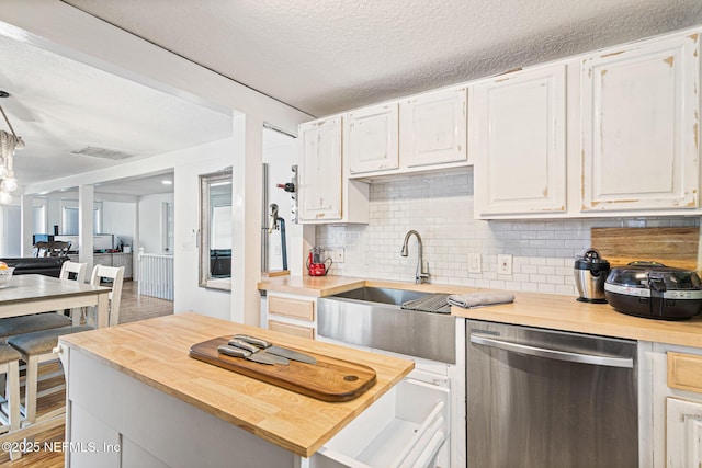 kitchen featuring a textured ceiling, white cabinetry, sink, backsplash, and stainless steel dishwasher